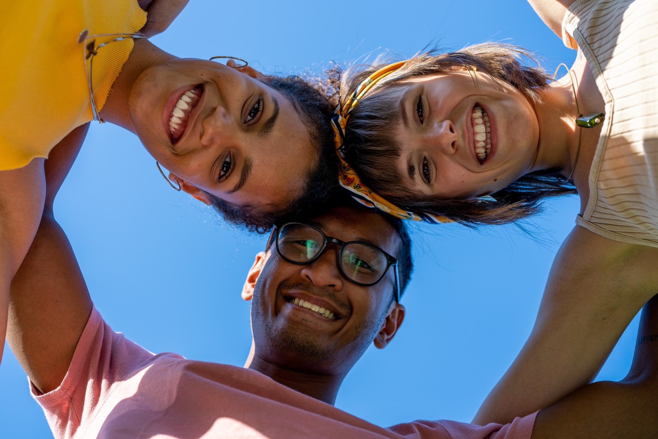 Multi ethnic group of friends looking at the camera and standing in circle, low angle view, happy people